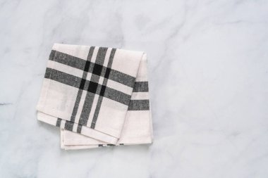 Mermer tezgahın üzerine katlanmış basit siyah desenli yeni mutfak havluları.