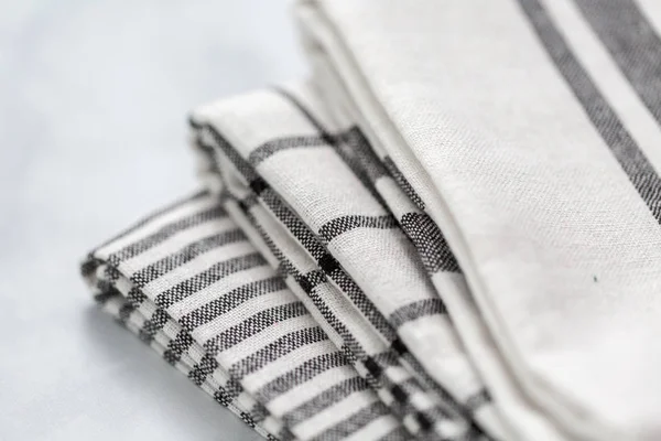 Mermer tezgahın üzerine katlanmış basit siyah desenli yeni mutfak havluları.