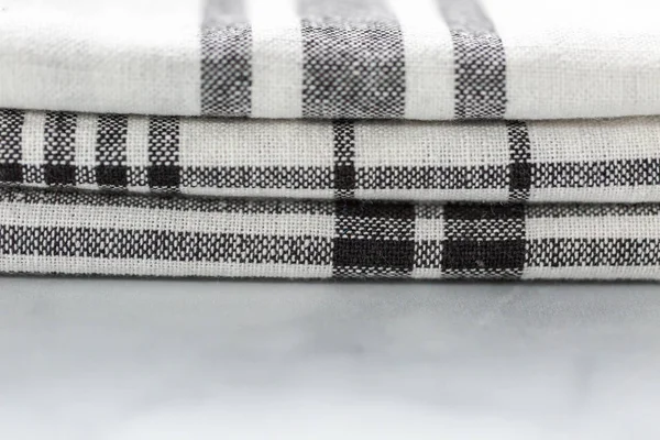 Mermer tezgahın üzerine katlanmış basit siyah desenli yeni mutfak havluları.