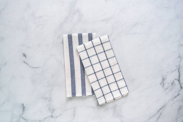 New kitchen towels with simple blue pattern folded on marble counter.