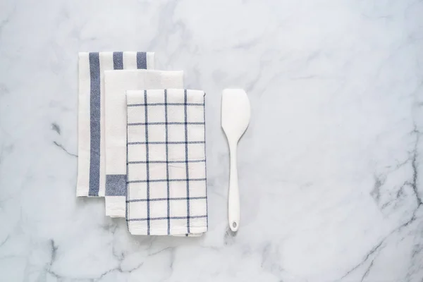 New kitchen towels with simple blue pattern folded on marble counter.