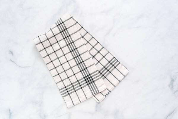 New kitchen towels with simple black pattern folded on marble counter.