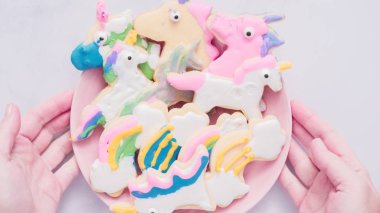 Pembe plaka üzerine Kraliyet krema şeker kurabiye şeklinde unicorn süslenmiş.