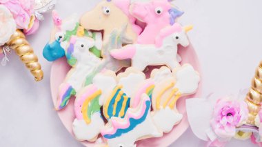 Pembe plaka üzerine Kraliyet krema şeker kurabiye şeklinde unicorn süslenmiş.