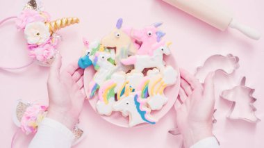 Pembe plaka üzerine Kraliyet krema şeker kurabiye şeklinde unicorn süslenmiş.