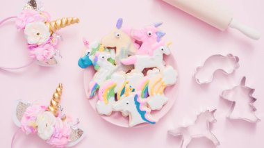 Pembe plaka üzerine Kraliyet krema şeker kurabiye şeklinde unicorn süslenmiş.