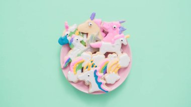 Pembe plaka üzerine Kraliyet krema şeker kurabiye şeklinde unicorn süslenmiş.