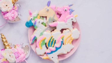Pembe plaka üzerine Kraliyet krema şeker kurabiye şeklinde unicorn süslenmiş.