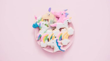 Pembe plaka üzerine Kraliyet krema şeker kurabiye şeklinde unicorn süslenmiş.