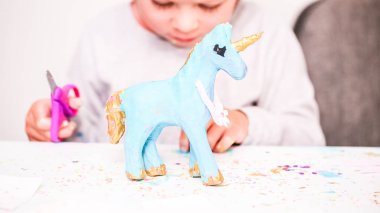 Küçük kızlar kağıt mache unicorn glitter ve kağıt çiçeklerle dekorasyon.