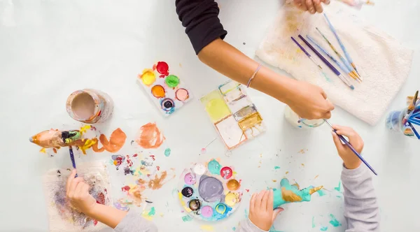 Step by step. Little girls painting paper mache unicorn with acrylic paint.