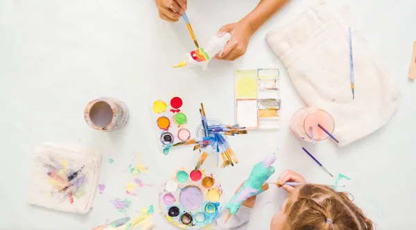 Step by step. Little girls painting paper mache unicorn with acrylic paint.