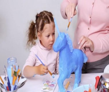 Adım adım. Anne ve kızı boyama kağıt mache unicorn mavi ile birlikte boya