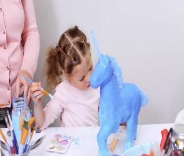 Adım adım. Anne ve kızı boyama kağıt mache unicorn mavi ile birlikte boya