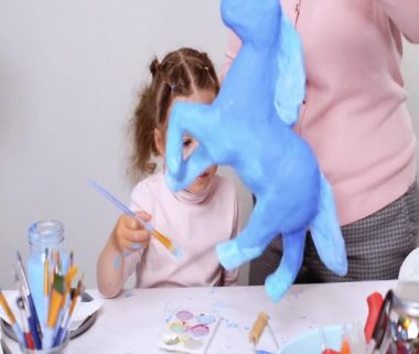 Adım adım. Anne ve kızı boyama kağıt mache unicorn mavi ile birlikte boya.