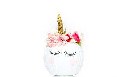 Zanaat balkabağı beyaz boyalı ve tek boynuzlu at beyaz arka plan üzerinde olarak pembe çiçeklerle süslenmiş.