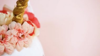Görünümü kapatın. Zanaat balkabağı beyaz boyalı ve tek boynuzlu at üzerinde pembe bir arka plan olarak pembe çiçeklerle süslenmiş