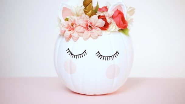 クラフトかぼちゃ塗られる白とピンクの背景にユニコーンとしてピンクの花で飾られました — ストック動画