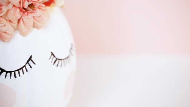 关闭视图 工艺南瓜漆白色和装饰粉红色的花朵作为独角兽在粉红色的背景 — 图库视频影像