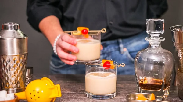 Whiskey sour cocktail garnished with orange and cherry.