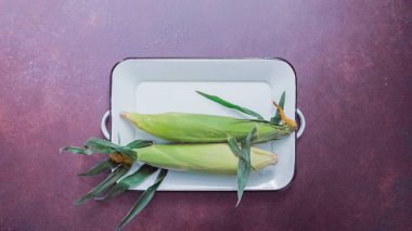 Adım adım. Beyaz matal tepside organik taze mısır.