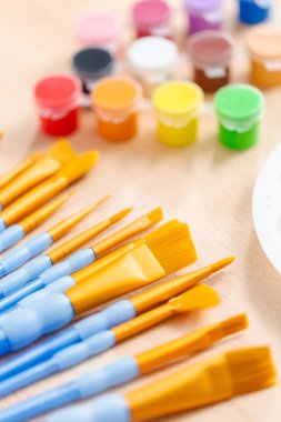 Yeni boya fırçaları ahşap bir masa üzerinde boya ile çeşitli.