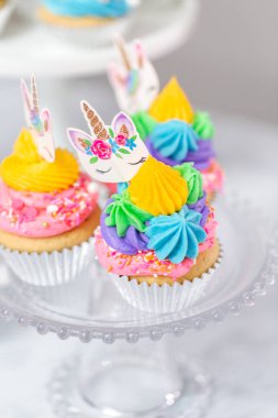 Tek boynuzlu at kek kek standları üzerine çok renkli buttercream krema ile.