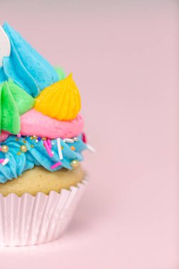 Tek boynuzlu at çok renkli buttercream buzlanma ve tek boynuzlu at cupcake topper üzerinde pembe bir arka plan ile cupcakes fantezi.