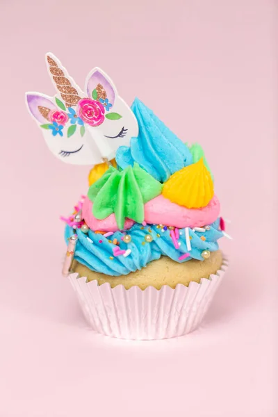 花哨的独角兽蛋糕与多色奶油冰和独角兽蛋糕礼帽在粉红色背景下 — 图库照片