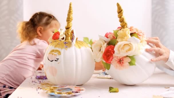 小さな女の子と彼女の工芸品をハロウィンのカボチャにユニコーンの母絵顔 — ストック動画