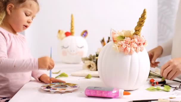母亲和女儿绘画面对一个独角兽和装饰工艺南瓜与花卉制作一个独角兽主题南瓜万圣节 — 图库视频影像
