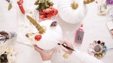 Küçük kız ve annesi boyama yüzü onun zanaat Cadılar Bayramı için kabak üzerinde bir tek boynuzlu at