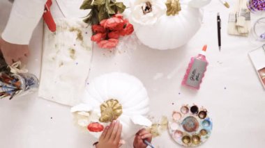 Üstten görünüm. Anne ve kızı yüzü bir tek boynuzlu at boyama ve zanaat kabak çiçekleri ile dekorasyon tema kabak Cadılar Bayramı için bir tek boynuzlu at yapmak