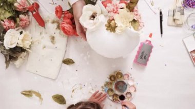 Üstten görünüm. Anne ve kızı yüzü bir tek boynuzlu at boyama ve zanaat kabak çiçekleri ile dekorasyon tema kabak Cadılar Bayramı için bir tek boynuzlu at yapmak