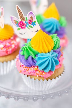 Tek boynuzlu at kek kek standları üzerine çok renkli buttercream krema ile.