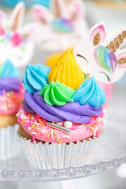 Tek boynuzlu at kek kek standları üzerine çok renkli buttercream krema ile.