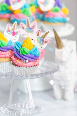 Tek boynuzlu at kek kek standları üzerine çok renkli buttercream krema ile.