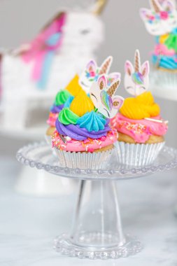 Tek boynuzlu at kek kek standları üzerine çok renkli buttercream krema ile.