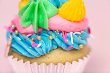 Tek boynuzlu at çok renkli buttercream buzlanma ve tek boynuzlu at cupcake topper üzerinde pembe bir arka plan ile cupcakes fantezi.