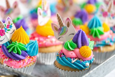 Metal tepsi üzerine çok renkli buttercream krema ile tek boynuzlu at cupcakes.