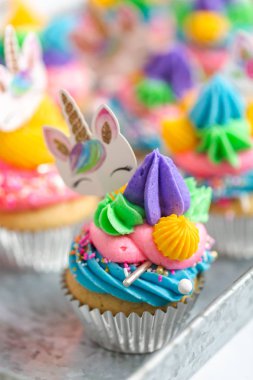 Metal tepsi üzerine çok renkli buttercream krema ile tek boynuzlu at cupcakes.