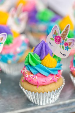 Metal tepsi üzerine çok renkli buttercream krema ile tek boynuzlu at cupcakes.