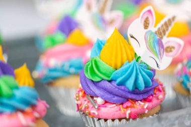 Metal tepsi üzerine çok renkli buttercream krema ile tek boynuzlu at cupcakes.