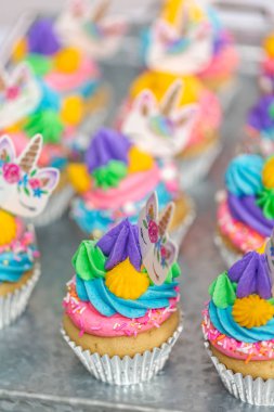 Metal tepsi üzerine çok renkli buttercream krema ile tek boynuzlu at cupcakes.