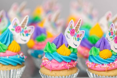 Metal tepsi üzerine çok renkli buttercream krema ile tek boynuzlu at cupcakes.