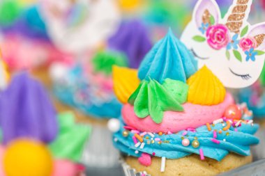 Metal tepsi üzerine çok renkli buttercream krema ile tek boynuzlu at cupcakes.