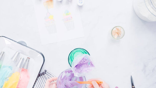 Step by step. Preparing piping bags with colorful buttercream frosting to decorate unicorn theme vanilla cupcakes.