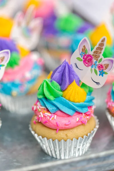 Metal tepsi üzerine çok renkli buttercream krema ile tek boynuzlu at cupcakes.