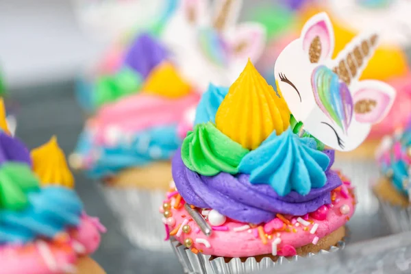 Metal tepsi üzerine çok renkli buttercream krema ile tek boynuzlu at cupcakes.