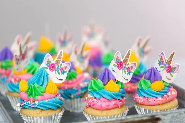 Metal tepsi üzerine çok renkli buttercream krema ile tek boynuzlu at cupcakes.